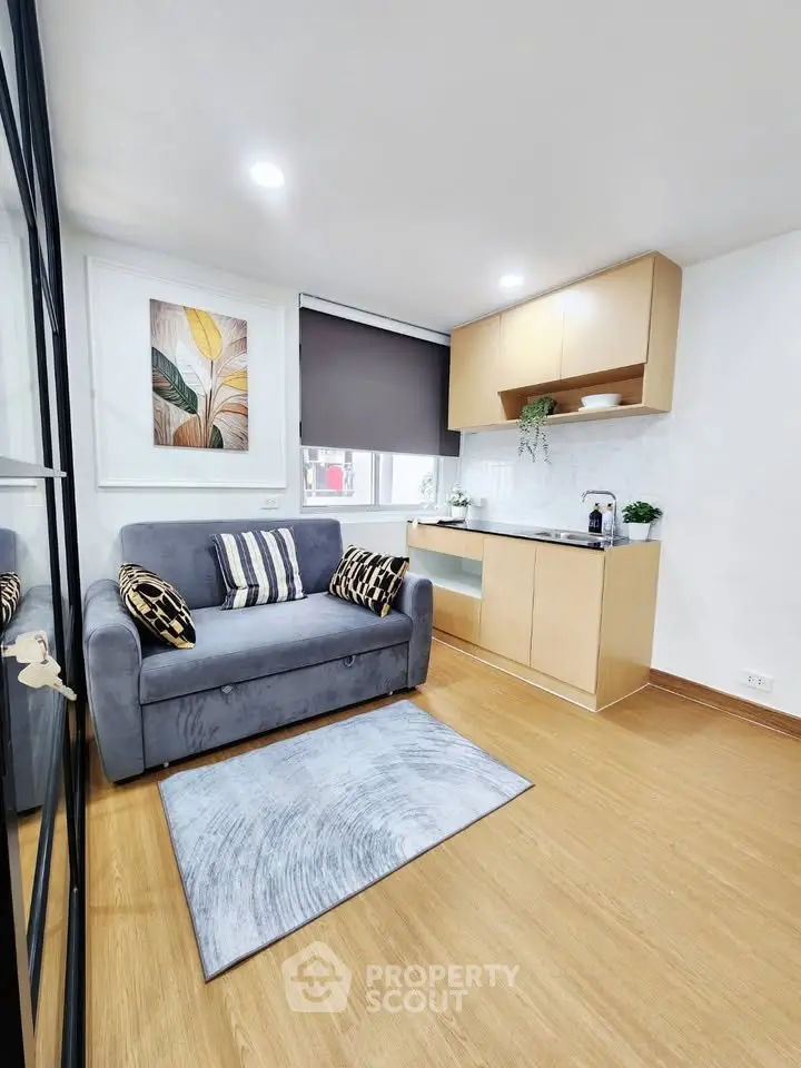 Modern compact living room with cozy sofa and stylish kitchenette in open layout apartment.