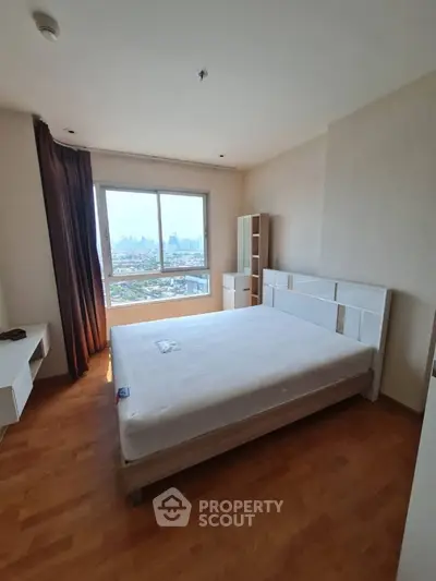 Spacious bedroom with city view and modern furnishings in high-rise apartment.