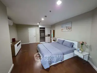 Spacious bedroom with modern decor and wooden flooring in a stylish apartment.