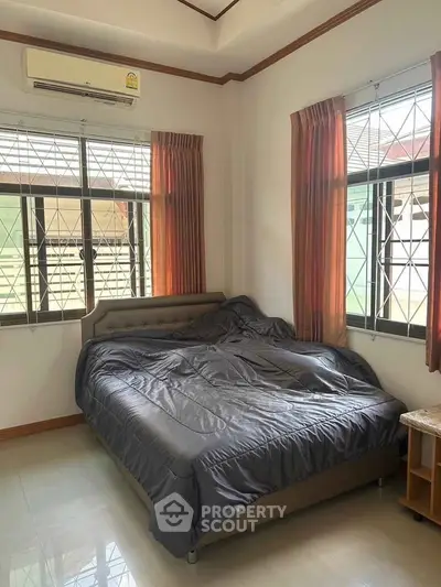 Cozy bedroom with large windows and natural light, featuring a comfortable bed and air conditioning.