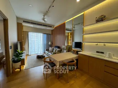 Modern living room with open kitchen, stylish decor, and large windows offering natural light.