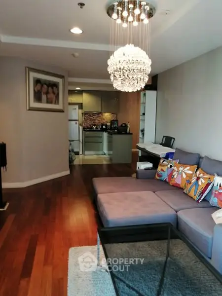 Stylish living room with modern chandelier and cozy sectional sofa in open layout apartment.
