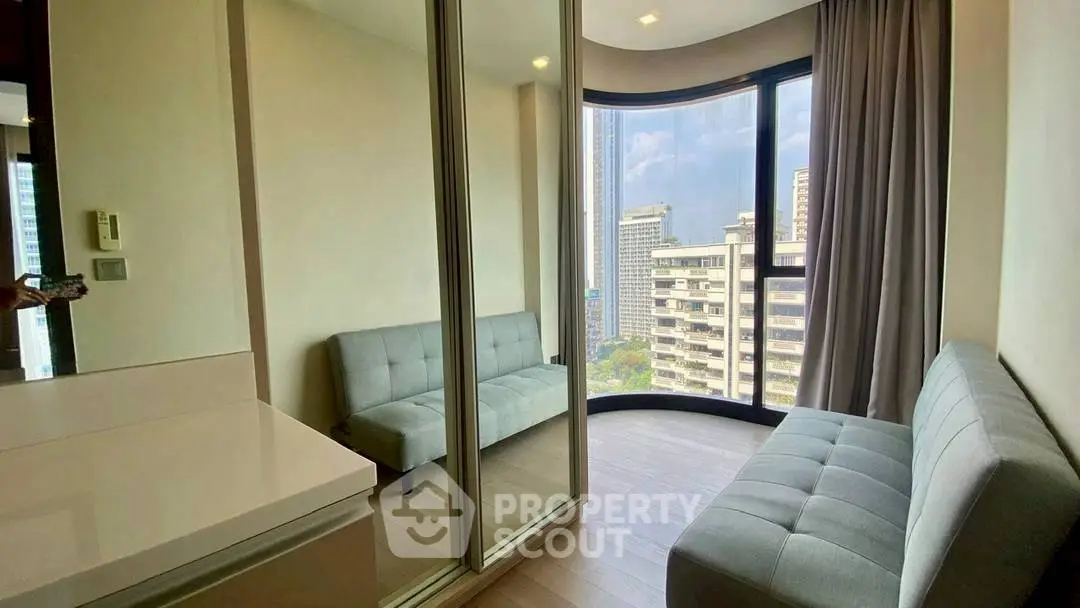 Modern living room with floor-to-ceiling windows and city view, featuring sleek furniture and ample natural light.