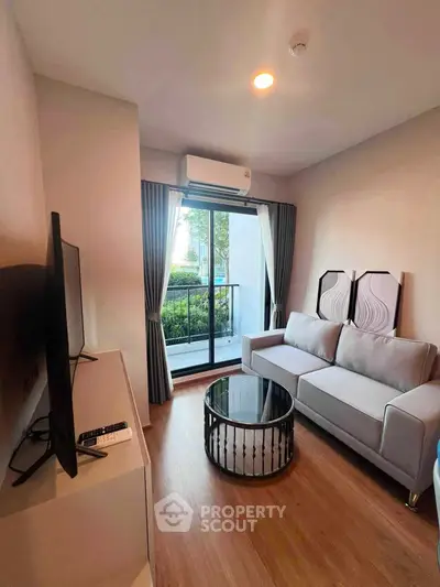 Modern living room with balcony view, featuring sleek furniture and natural light.