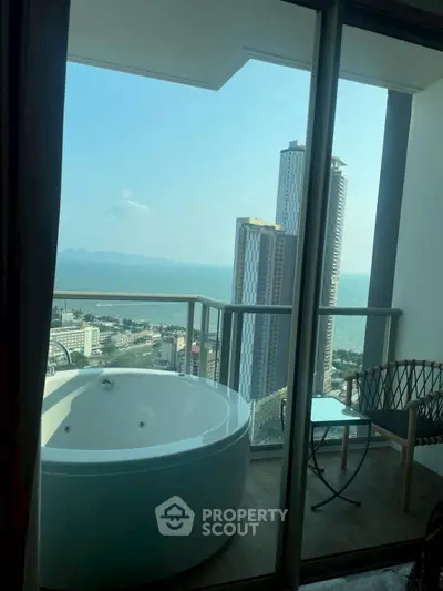 Luxurious balcony with stunning ocean view and private jacuzzi in high-rise apartment.