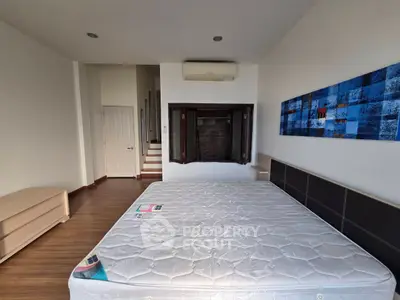 Spacious bedroom with modern decor and large bed, featuring stylish artwork and wooden flooring.