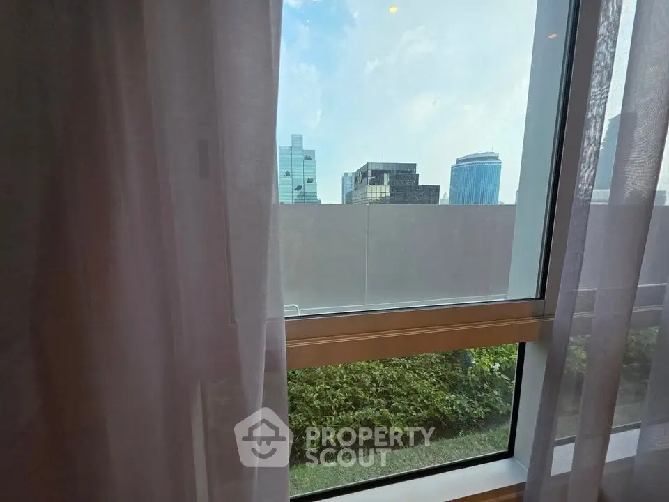 Modern city view from window with lush greenery and skyline backdrop