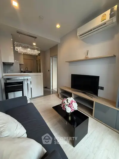 Modern living room with sleek furniture and open kitchen layout, featuring a cozy ambiance and stylish decor.