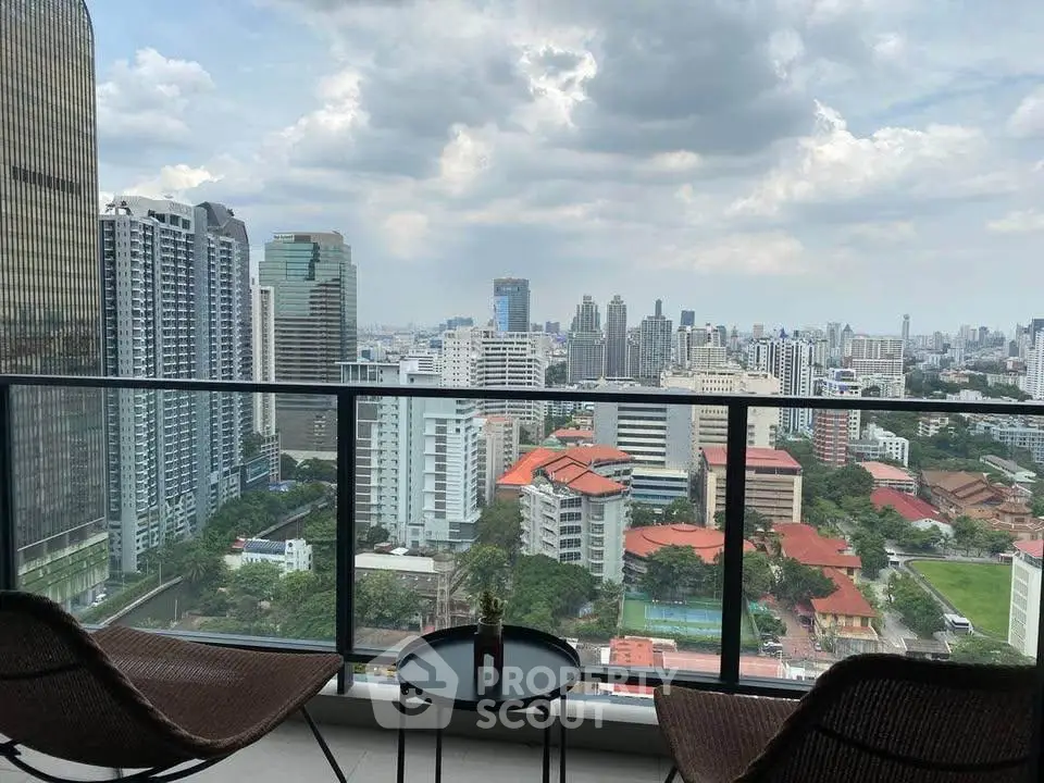 Stunning cityscape view from a modern balcony with seating area.