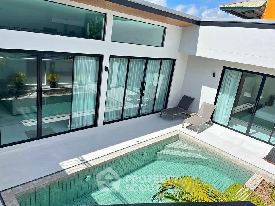 Modern villa with private pool and sleek glass doors in a sunny courtyard.