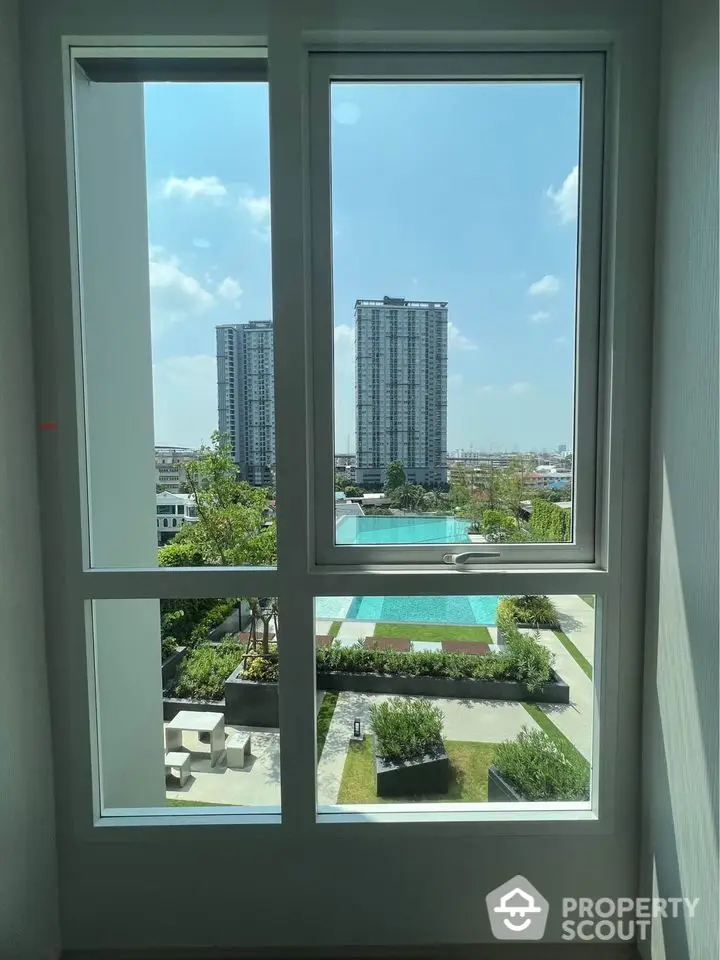 Stunning cityscape view from modern apartment window overlooking pool and garden.