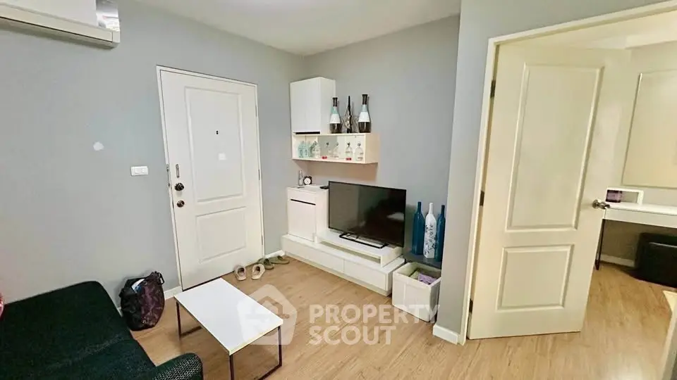 Cozy living room with modern decor and wooden flooring, featuring a TV and stylish shelving.
