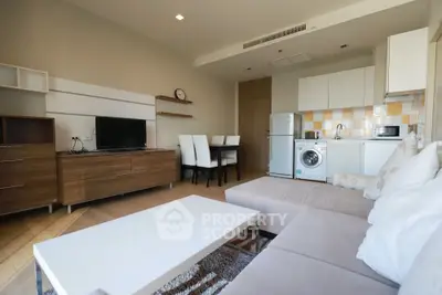 Modern living room with open kitchen, featuring cozy sofa and dining area.