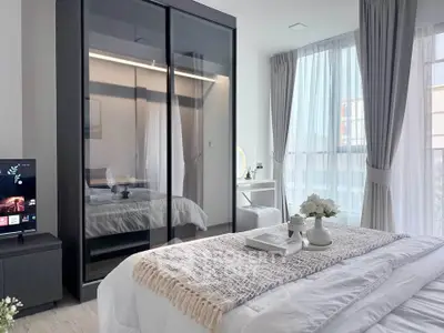 Modern bedroom with elegant decor and large windows offering natural light.
