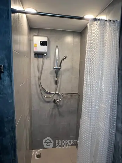 Modern shower area with sleek tiles and water heater in a compact bathroom.