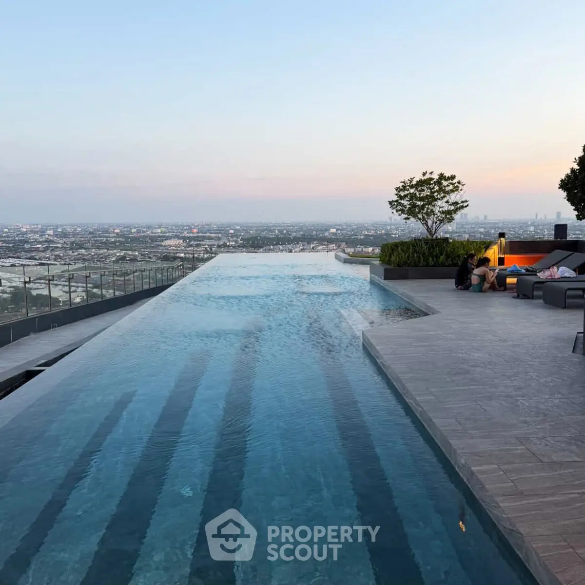 Luxurious rooftop infinity pool with stunning city skyline view at sunset.