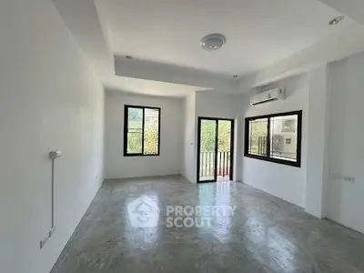 Spacious unfurnished living room with large windows and balcony access