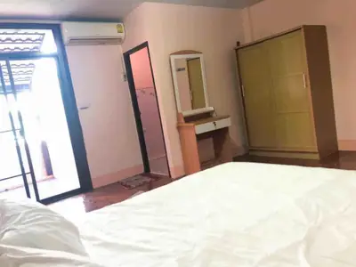 Cozy bedroom with balcony access, featuring air conditioning and wooden furniture for a comfortable living space.