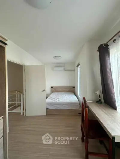 Bright and airy bedroom with wooden flooring and modern furnishings, perfect for a cozy retreat.