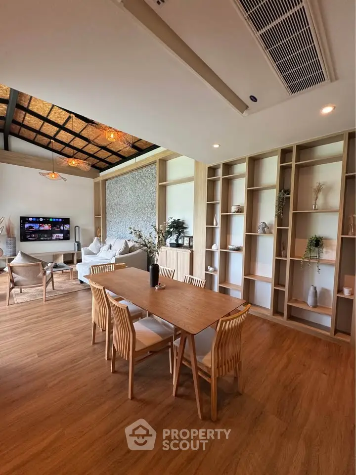 Spacious living room with modern decor and wooden flooring, featuring a cozy seating area and stylish dining table.