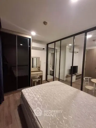 Modern bedroom with glass partition, sleek wardrobe, and cozy ambiance in a stylish apartment.