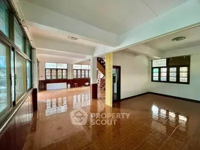 Spacious open-plan living area with large windows and glossy tiled floors