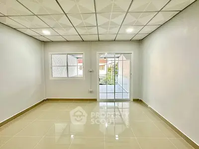 Spacious empty room with glossy tiled floor and large windows for natural light.