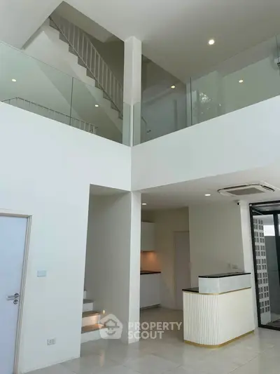Modern duplex interior with high ceilings and sleek design, featuring a stylish staircase and open layout.