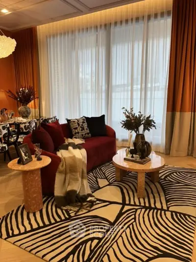Stylish living room with modern decor, vibrant red sofa, and elegant patterned rug.