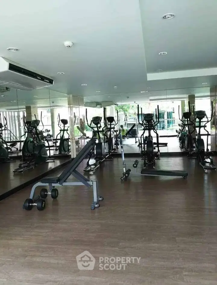 Spacious gym with modern exercise equipment and mirrored walls in a residential building.