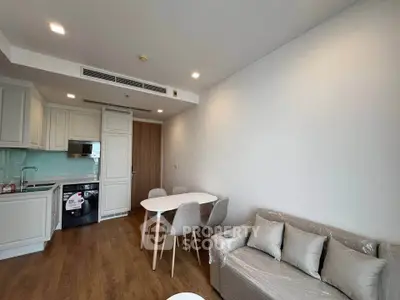 Modern living room with open kitchen, dining area, and cozy sofa in a stylish apartment.