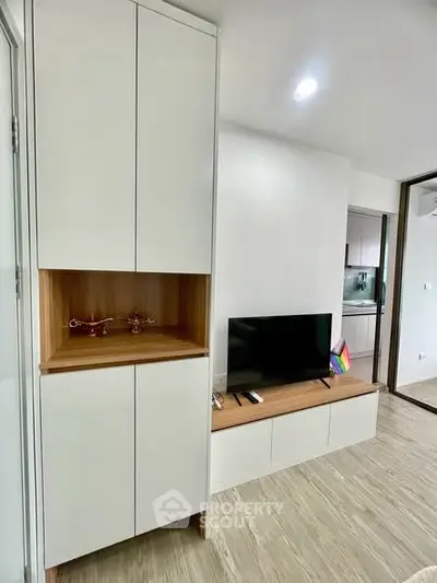 Modern living room with sleek cabinetry and TV setup, showcasing minimalist design and open layout.