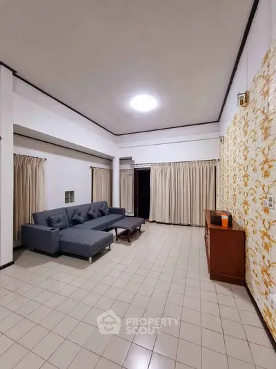 Spacious living room with modern gray sectional sofa and elegant gold-accented wall decor.