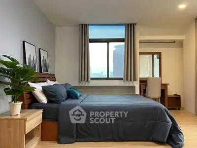 Modern bedroom with stylish decor and city view window, featuring a cozy bed and elegant furnishings.