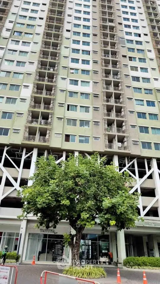 Modern high-rise building exterior with lush greenery and entrance view.