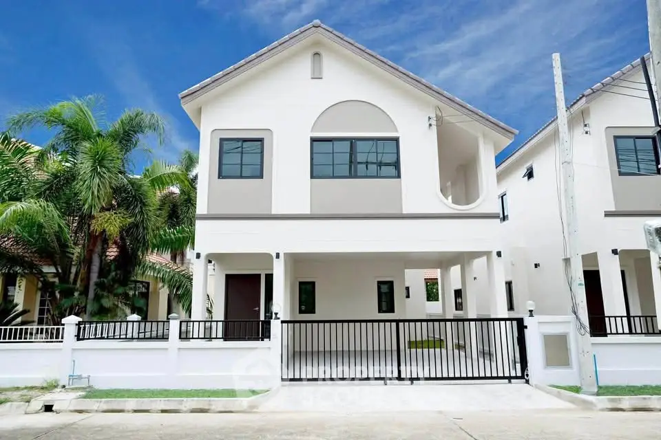 Modern two-story house with gated entrance and lush palm trees, perfect for family living.