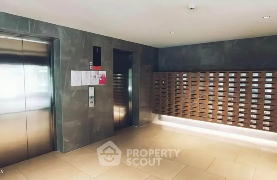 Modern apartment building lobby with elevators and mailboxes, sleek design and ample lighting.