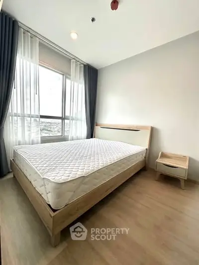 Bright and airy bedroom with large window and modern furnishings in a stylish apartment.