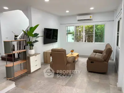 Modern living room with cozy seating and natural light, featuring a sleek TV setup and stylish decor.