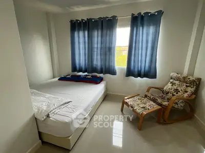 Cozy bedroom with natural light, featuring a comfortable bed and stylish chair, perfect for relaxation.