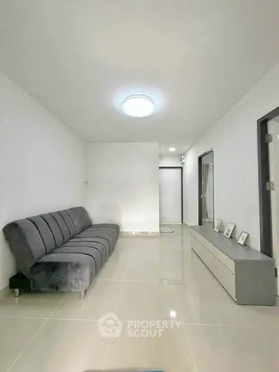 Modern minimalist living room with sleek gray sofa and glossy tiled floor