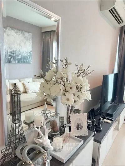 Elegant living room with modern decor, featuring a TV, stylish furniture, and decorative accents.