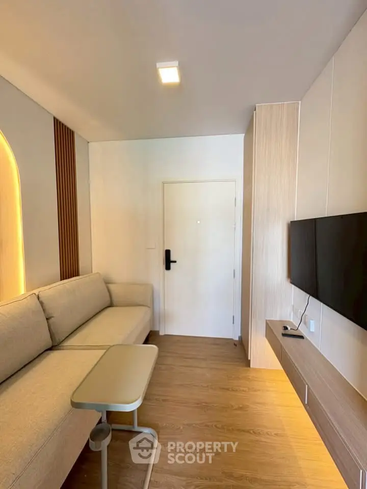 Modern living room with sleek design, featuring a cozy sofa and wall-mounted TV, perfect for relaxation.