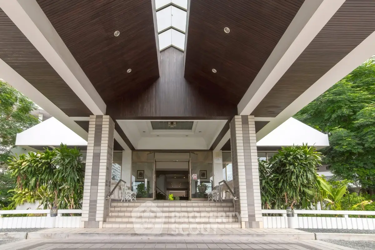 Elegant building entrance with modern architecture and lush greenery