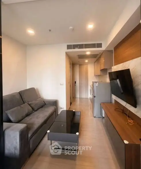 Modern living room with sleek furniture and wall-mounted TV in a cozy apartment.