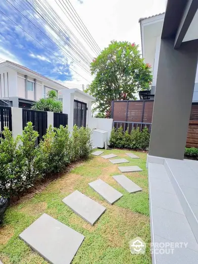 Charming garden path with stepping stones in a modern residential backyard, surrounded by lush greenery and privacy fence.