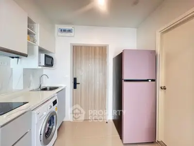 Modern kitchen with pink fridge, washing machine, and sleek cabinetry