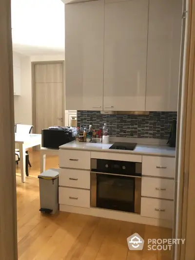 Modern kitchen with sleek cabinetry and built-in oven in a cozy apartment setting.