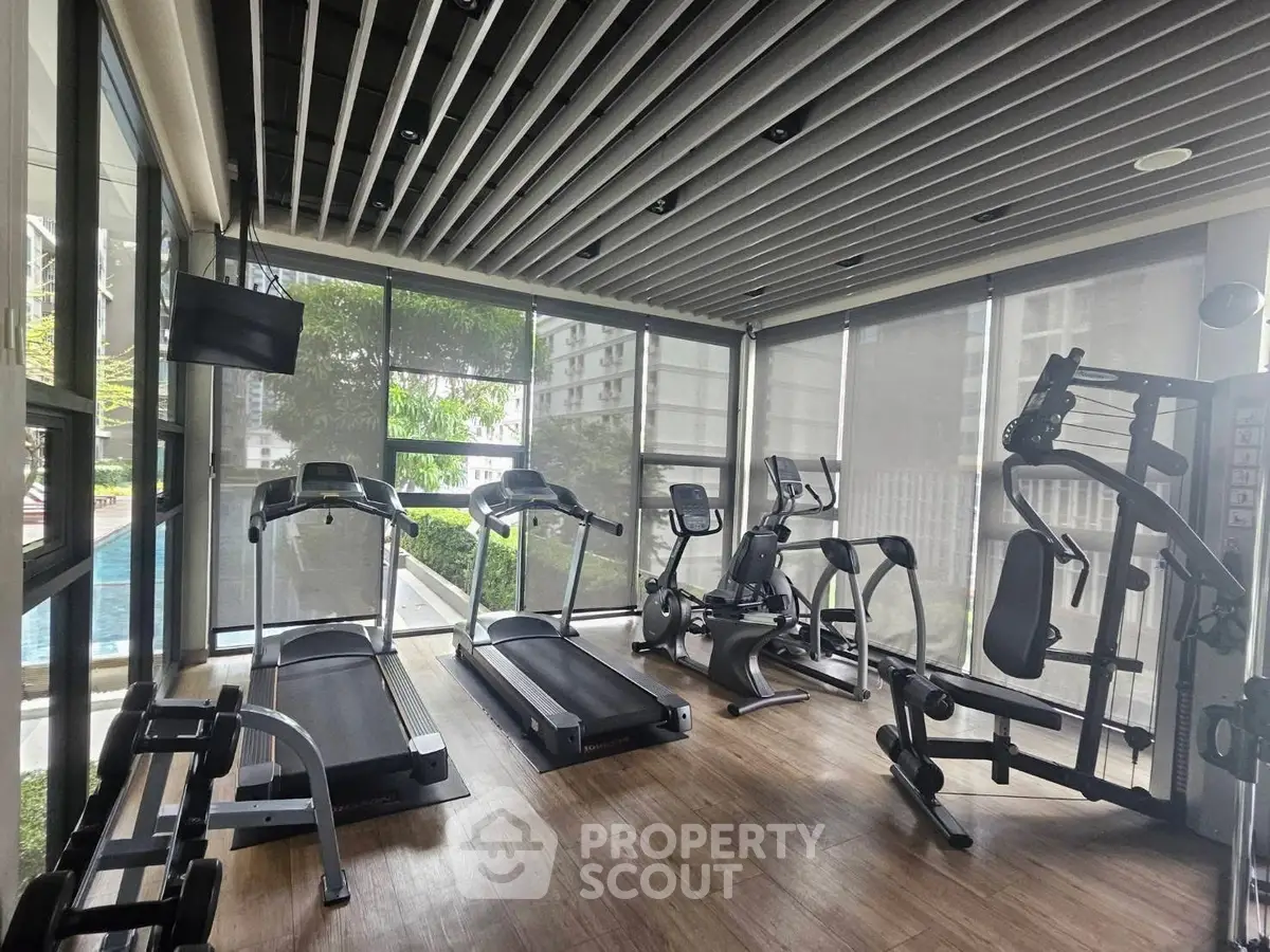 Modern gym with state-of-the-art equipment and pool view in luxury apartment complex.
