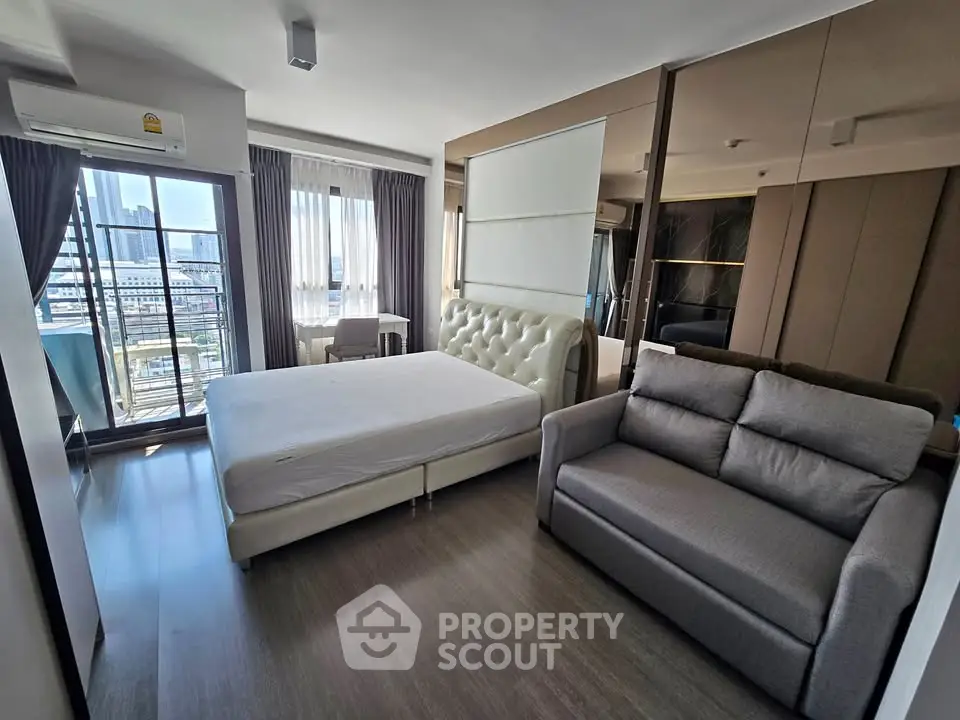 Modern bedroom with city view, featuring a plush bed and cozy sofa in a stylish apartment.